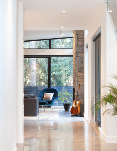 Wide hallway with egg chair and view to open-concept kitchen and living room in Whistler Passive House