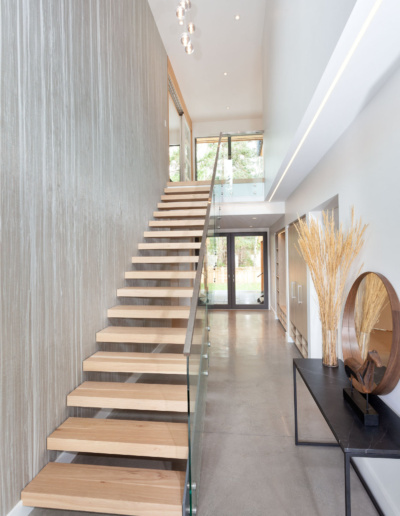 Contemporary staircase with glass railing and natural light in Whistler custom home