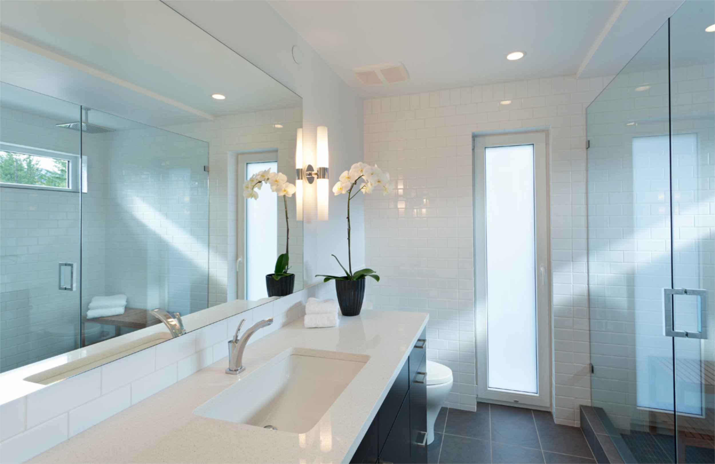Contemporary Bathroom Design - Rainbow Home Modern white bathroom with soaking tub and glass door in Whistler custom home