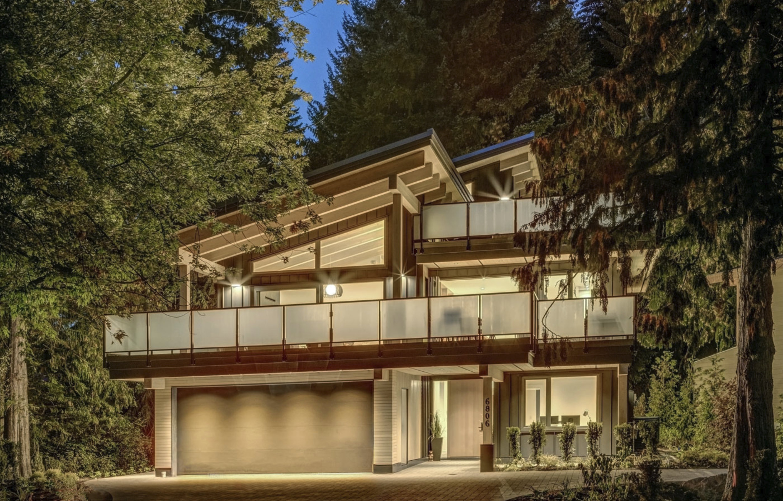 Exterior Night View - Nestled in Nature Nighttime exterior of custom Whistler home showing illuminated lower level and garage
